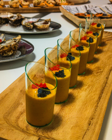 Salmorejo de tomate amarillo, cremosos y elegante, presentado de forma gourmet para un evento exclusivo.