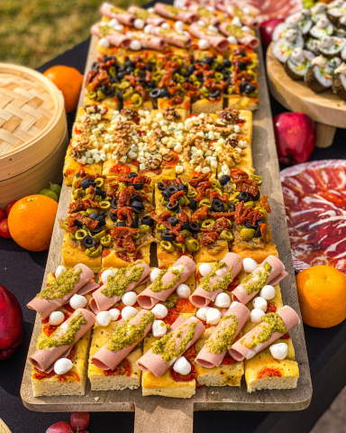 Tabla con focaccias variadas recién horneadas, con diferentes ingredientes y presentadas de forma elegante para evento gourmet.