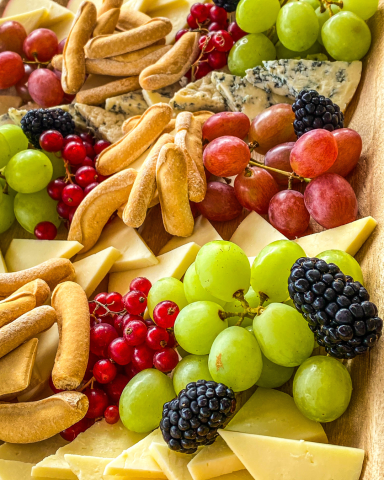 Tabla de quesos variados acompañados de picos y fruta fresca, presentada de manera elegante para un catering gourmet en eventos.