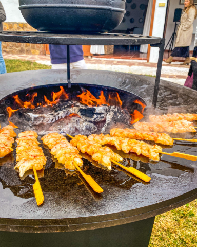 Brochetas de langostinos en la Ofyr | Catering en Valencia Brochetas de carne asándose sobre una parrilla con fuego intenso.