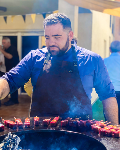 Chef cocinando en la Ofyr | Catering en Valencia Chef profesional cocinando platos gourmet sobre Ofyr al aire libre, mostrando la preparación en vivo para un evento