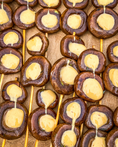 Brochetas de setas portobello marinadas en miso, presentadas elegantemente sobre una bandeja gourmet para un evento exclusivo.