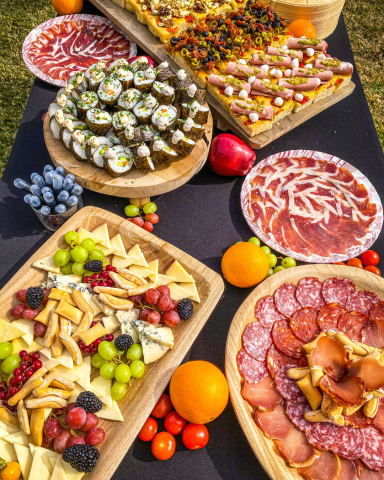 Mesa elegante con variedad de quesos, ibéricos, sushi y focaccias artesanas, preparada para un evento gourmet.