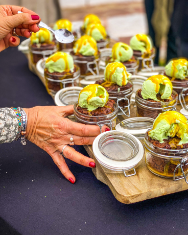 Brownie de chocolate acompañado con helado de pistacho y especias ras el hanout, presentado como postre gourmet para un evento exclusivo.