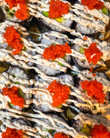 Makis rellenos de verduras frescas, decorados con huevas de alga nori, presentados de manera elegante para un evento gourmet.