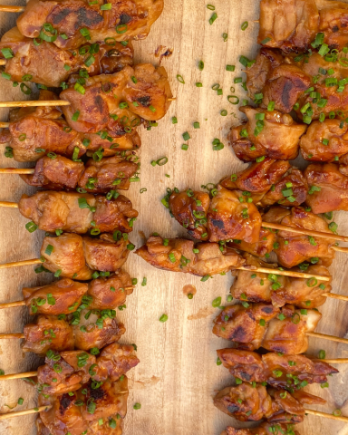 Brochetas de pollo estilo Pekín, cocinadas y presentadas de forma gourmet, listas para servir en un evento exclusivo.