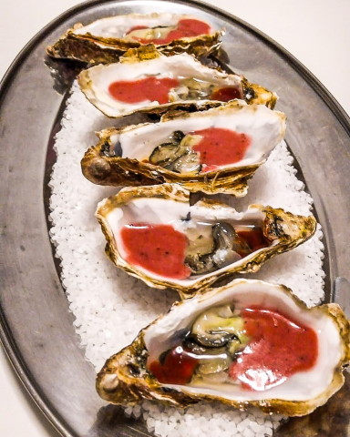 Ostras frescas acompañadas de estofado de fresas y kimchi, presentadas como un plato gourmet innovador para eventos elegantes